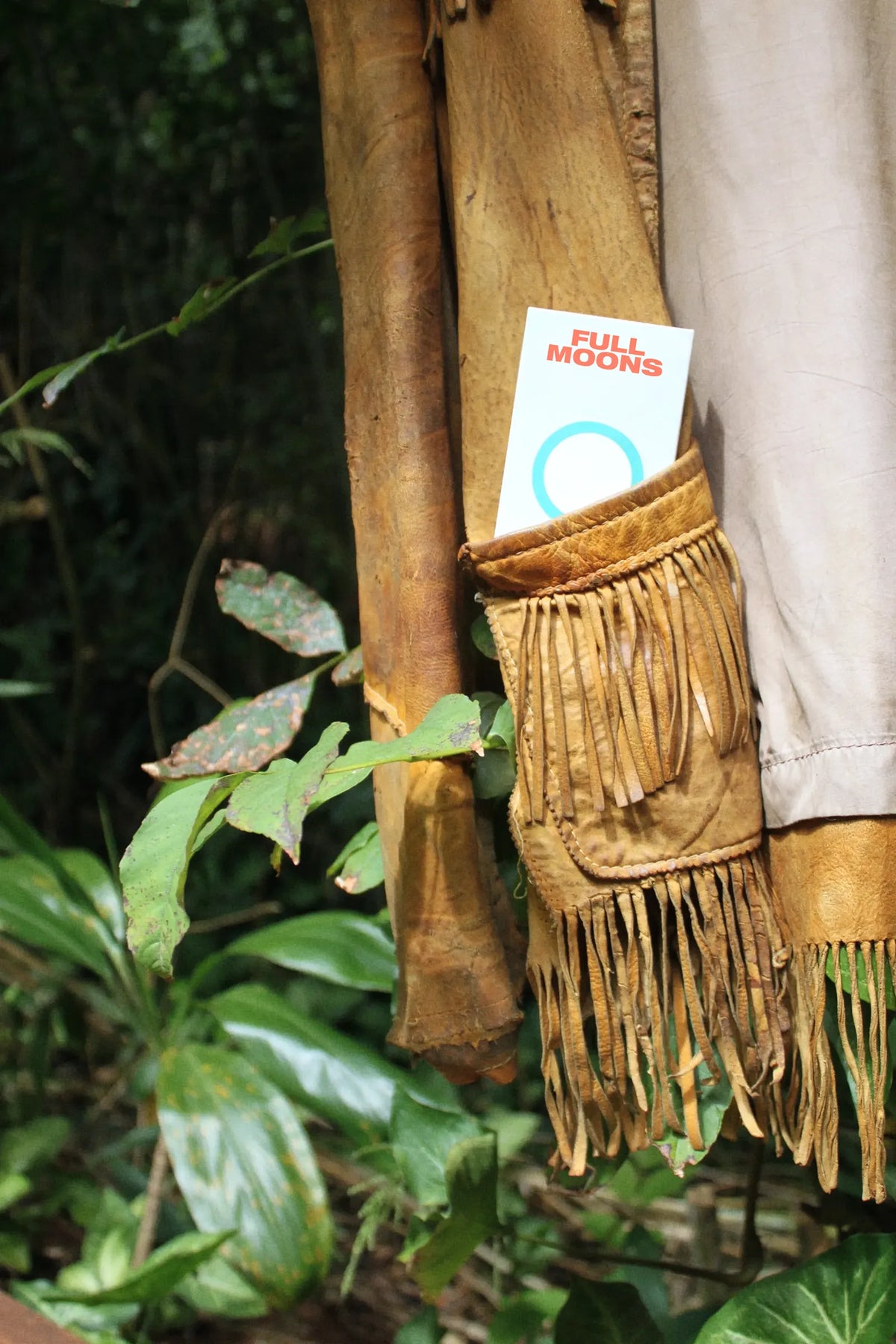 A pack of Full Moons tucked into a fringed leather pouch hanging among tropical plants