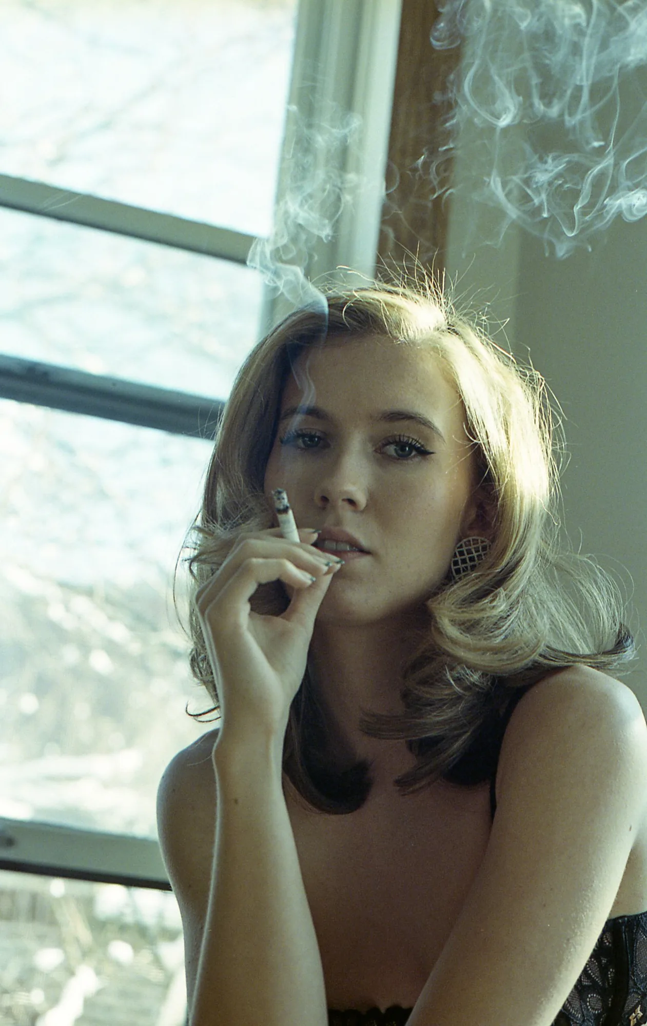 Portrait of a woman smoking by a window, vintage vibe