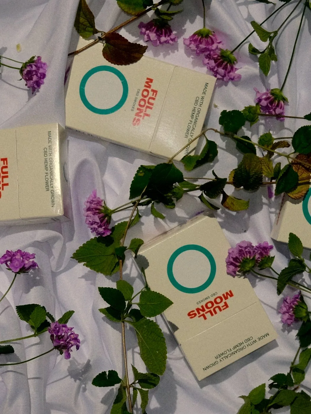 Full Moons packs laid among fresh purple blooms on white linen