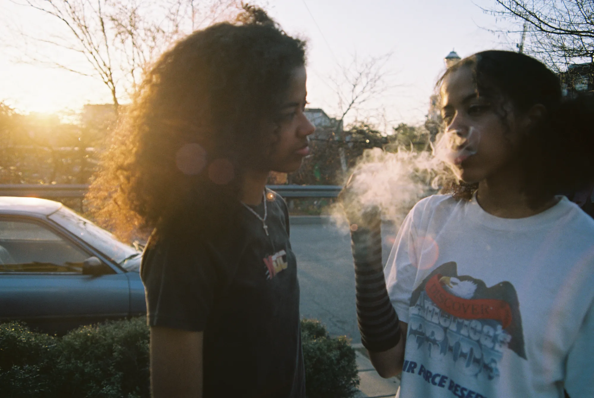 Two friends at golden hour, one exhaling smoke
