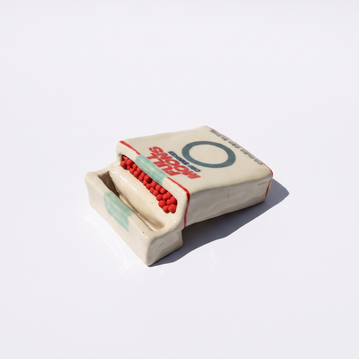 The Memento ceramic matchbox in Cooled, lying on its side with matches showing