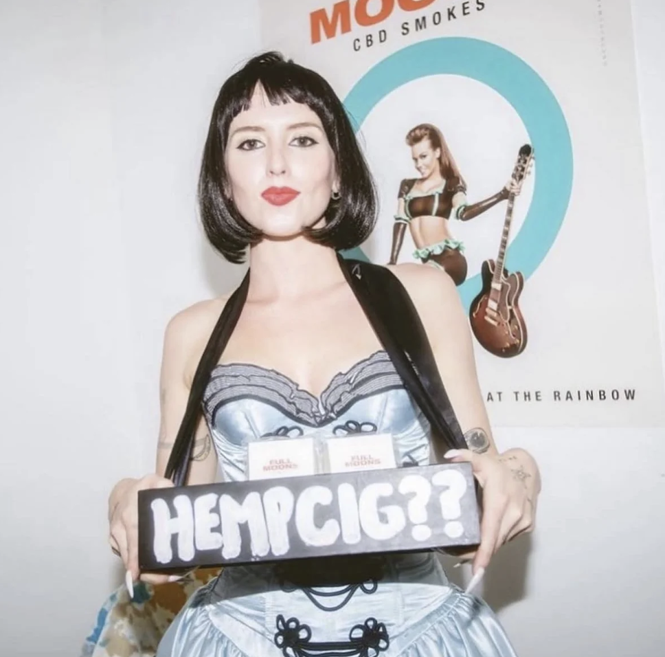 Marion Brooks at a Full Moons event, holding a HEMPCIG sandwich board with packs